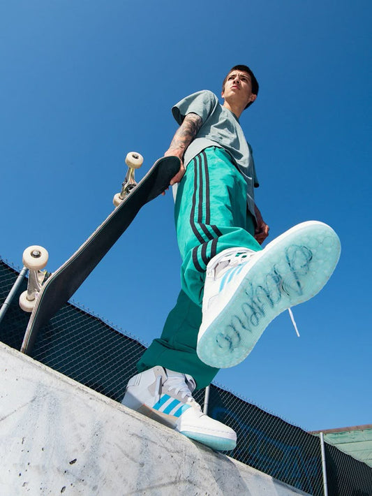 treetwear enthusiast in urban fashion wearing affordable streetwear brand tracksuit and sneakers, holding a skateboard at a skatepark, showcasing streetwear style and street culture.