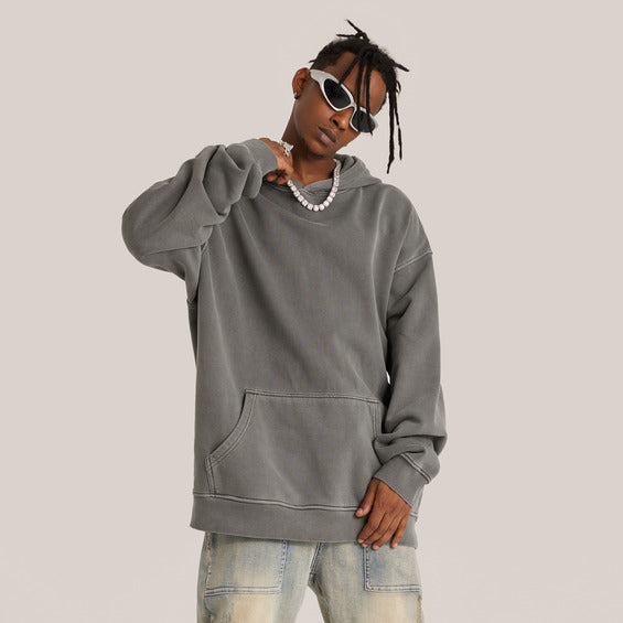 Person wearing a gray hoodie and sunglasses on a plain background